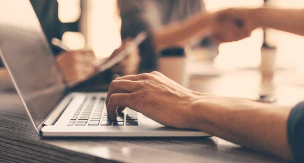 man using a laptop and shaking hands