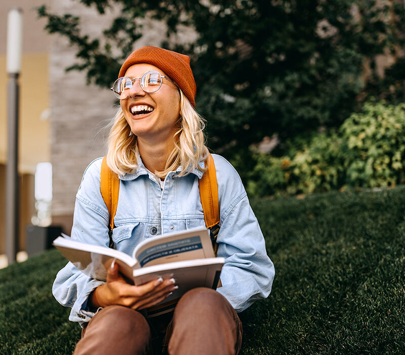 Young cheerful hipster woman studying outdoors in campus