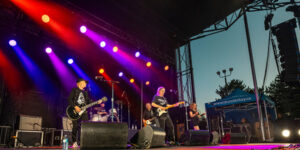 Musicians perform on an outdoor stage under colourful lighting during the Summer Sendoff event by City of Thunder Bay.